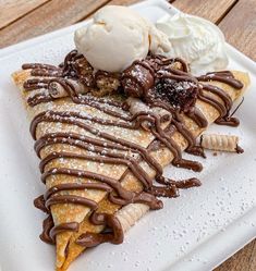 a white plate topped with lots of food on top of a wooden table next to a scoop of ice cream