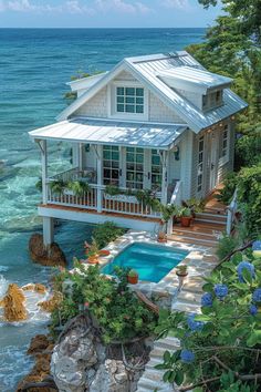 a house with a pool in front of it next to the ocean and rocks on the shore