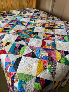 a bed with a colorful quilt on top of it