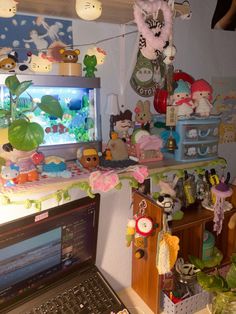 an open laptop computer sitting on top of a wooden desk next to a shelf filled with stuffed animals