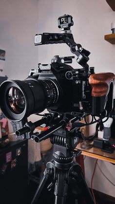 a video camera sitting on top of a tripod in front of a wooden table