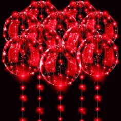 many red balls are hanging from strings on a black background with stars and sparkles