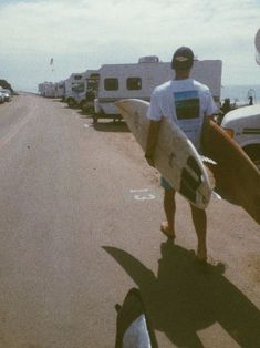 a man is carrying his surfboard down the road