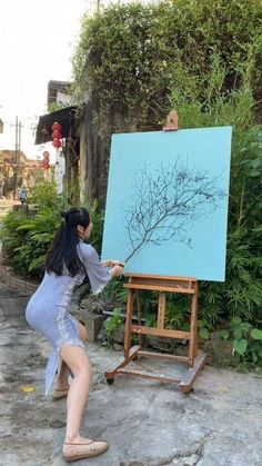 a woman is painting on an easel outside