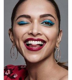 a woman with bright blue eyeshades and red lipstick is smiling at the camera