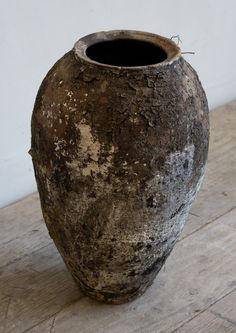 an old vase sitting on top of a wooden table next to a wall and floor