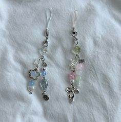 two charms on a white sheet are hanging from the end of each beaded cord