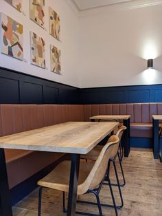 an empty restaurant with wooden tables and benches in the center, along with pictures on the wall