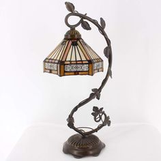 a table lamp with a glass shade on it's base and leaves hanging off the side