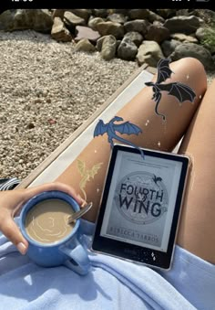 a woman is sitting on the ground with her legs crossed holding a tablet and cup of coffee