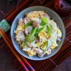 a bowl filled with food next to chopsticks