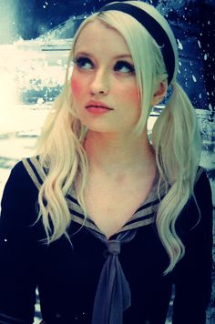 a woman with long blonde hair wearing a black shirt and tie, standing in the snow