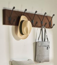 a hat hanging on a coat rack with hooks and two totes in front of it