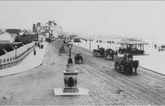 an old black and white photo of horse drawn carriages on a road near the water