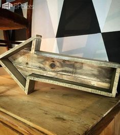 an old wooden tray sitting on top of a table next to a chair and wall