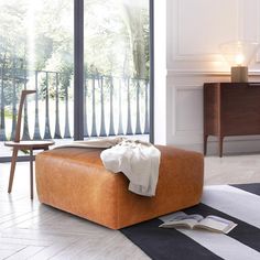 an orange ottoman sitting on top of a black and white striped floor next to a window