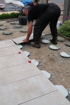 a man laying tile on the ground