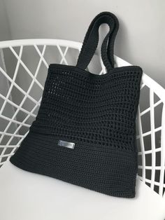 a black crocheted bag sitting on top of a white chair