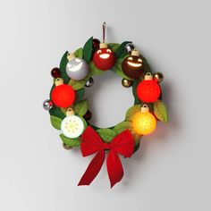 a christmas wreath with ornaments hanging from it's sides and a red bow on the front