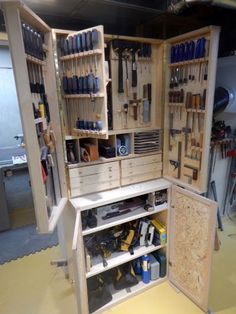 an open cabinet with tools inside of it in a room filled with workbenches