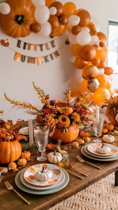 a table set for thanksgiving dinner with pumpkins and balloons