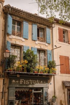 an old building with blue shutters and flowers on the balcony