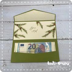 a green and white christmas card with pine branches on the front, two twenty euros bill in the back