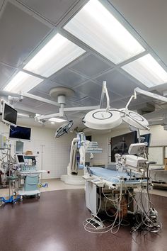 an operating room with medical equipment and monitors on the wall, overhead lighting in the ceiling