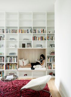 a woman laying on top of a bed in a living room next to a book shelf