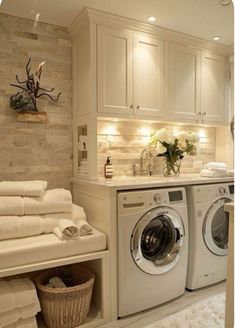 a washer and dryer in a room with white towels on the shelves next to each other