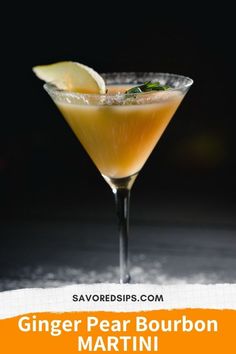 a glass filled with an orange drink on top of a wooden table