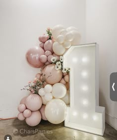 balloons and flowers are arranged in the shape of a number one on a white wall