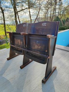 two wooden chairs sitting on top of a cement floor next to a blue swimming pool