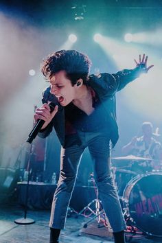 a man standing on top of a stage holding a microphone