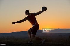 a man in red shirt and black shorts holding a frisbee on top of a hill