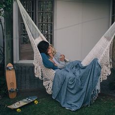 a woman sitting in a hammock reading a book