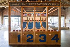 an arcade machine with basketballs in it and numbers on the front, behind which is a sign that reads portland recreation club