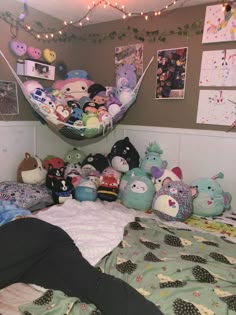 a bed with many stuffed animals on it and a hammock hanging from the ceiling