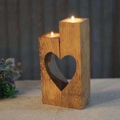 a wooden candle holder with a heart cut out of it next to a wedding cake