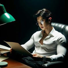 a woman sitting at a desk in front of a lamp reading a piece of paper