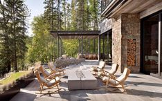 an outdoor living area with chairs, table and fire pit in the middle of it