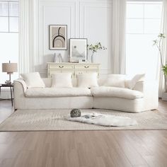 a living room with white furniture and wood flooring, including a large sectional couch