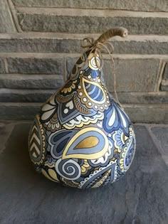 a blue and yellow vase sitting on top of a stone floor next to a brick wall