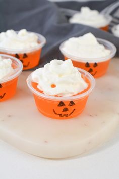 small plastic cups with whipped cream and jack - o'- lantern faces on them