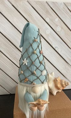 a blue stuffed animal sitting on top of a wooden table next to seashells