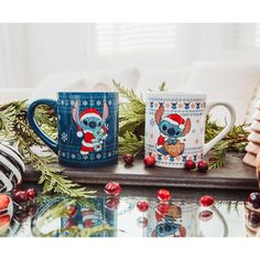 two christmas themed coffee mugs sitting on top of a table