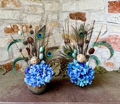 two vases filled with blue flowers and peacock feathers