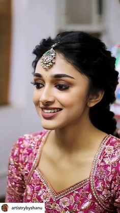 a woman in a pink dress smiling and wearing a head piece with jewels on it