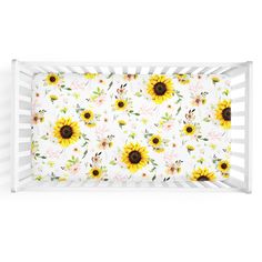 a white crib bed with sunflowers and leaves on the side, in front of a white background