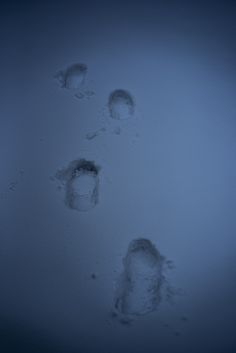 three footprints in the snow on a dark day with no one around them or someone else